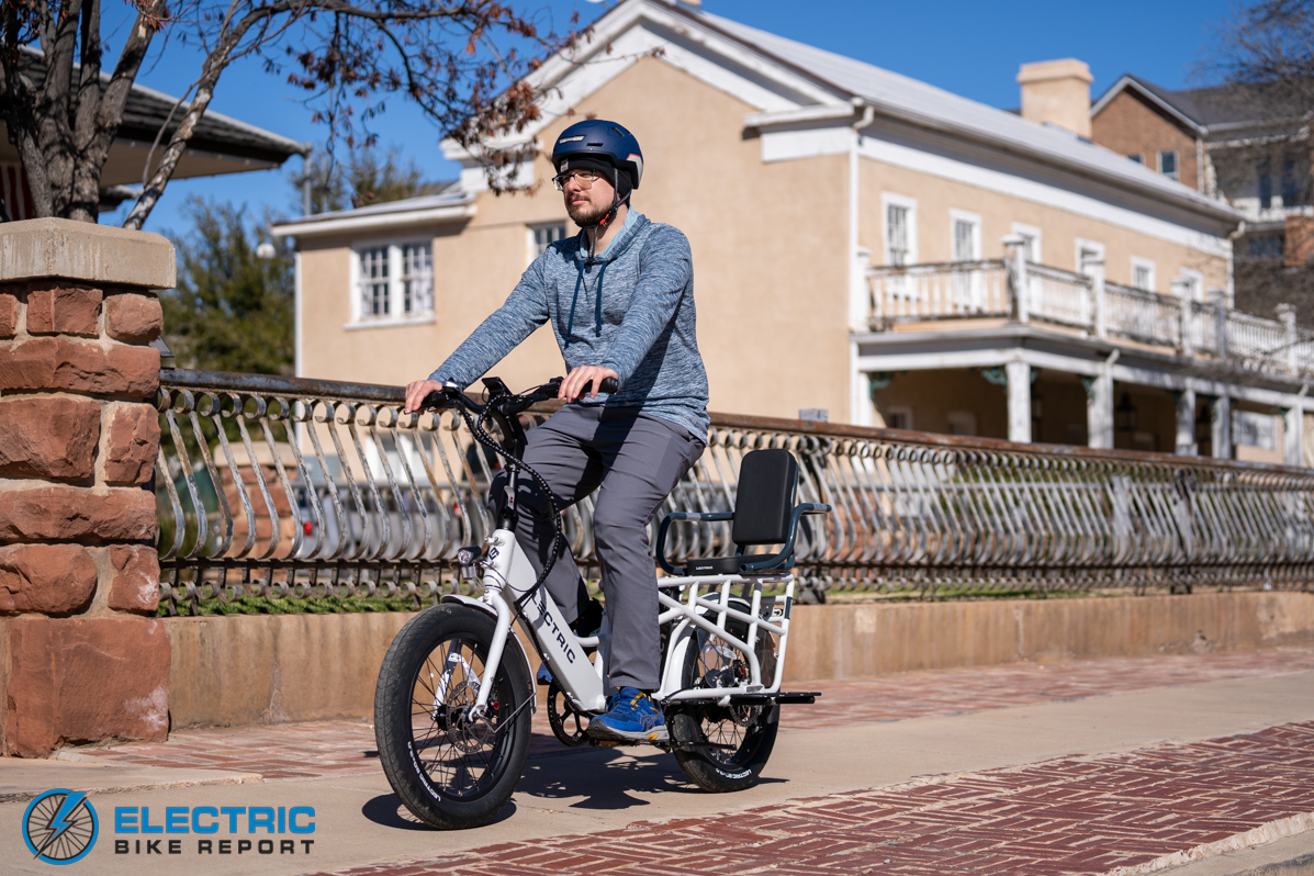 Lectric XPedition riding on a city path in front of a house